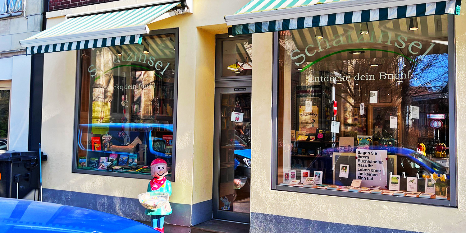 Außenansicht der Buchhandlung "Die Schatzinsel" an der Neubrückenstraße in Münster, beeinträchtigt von einem Bauzaun.